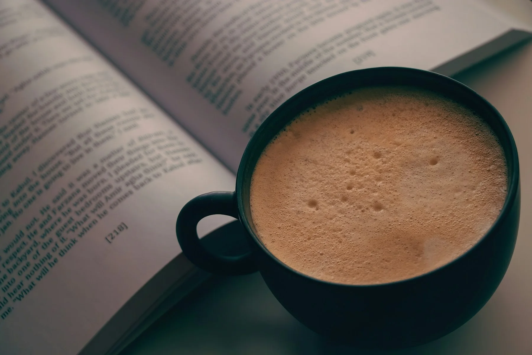 Kop koffie naast een open boek als beeld bij kleine dagelijkse routines